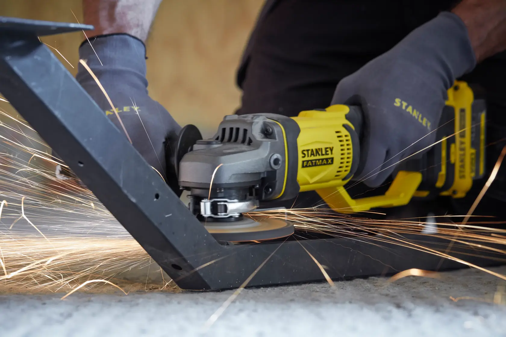 STANLEY SCG400M2K-KR amoladora angular cortando metal con chispas, toma cercana, operario con guantes.