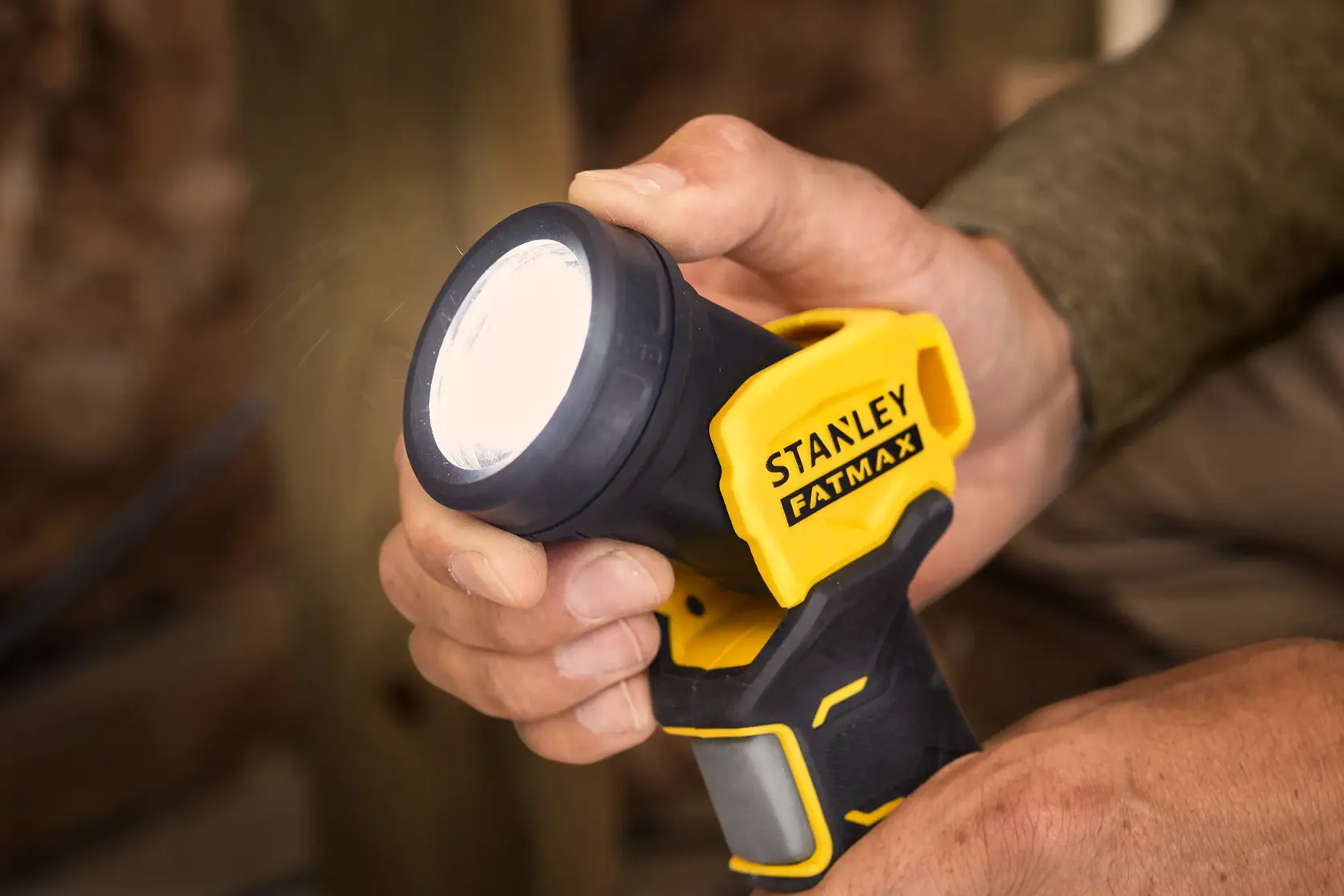 Linterna Stanley Fatmax en mano, amarillo y negro, SKUs SCL020, SCL020-KR, SCL020-B2, fotografía close-up.