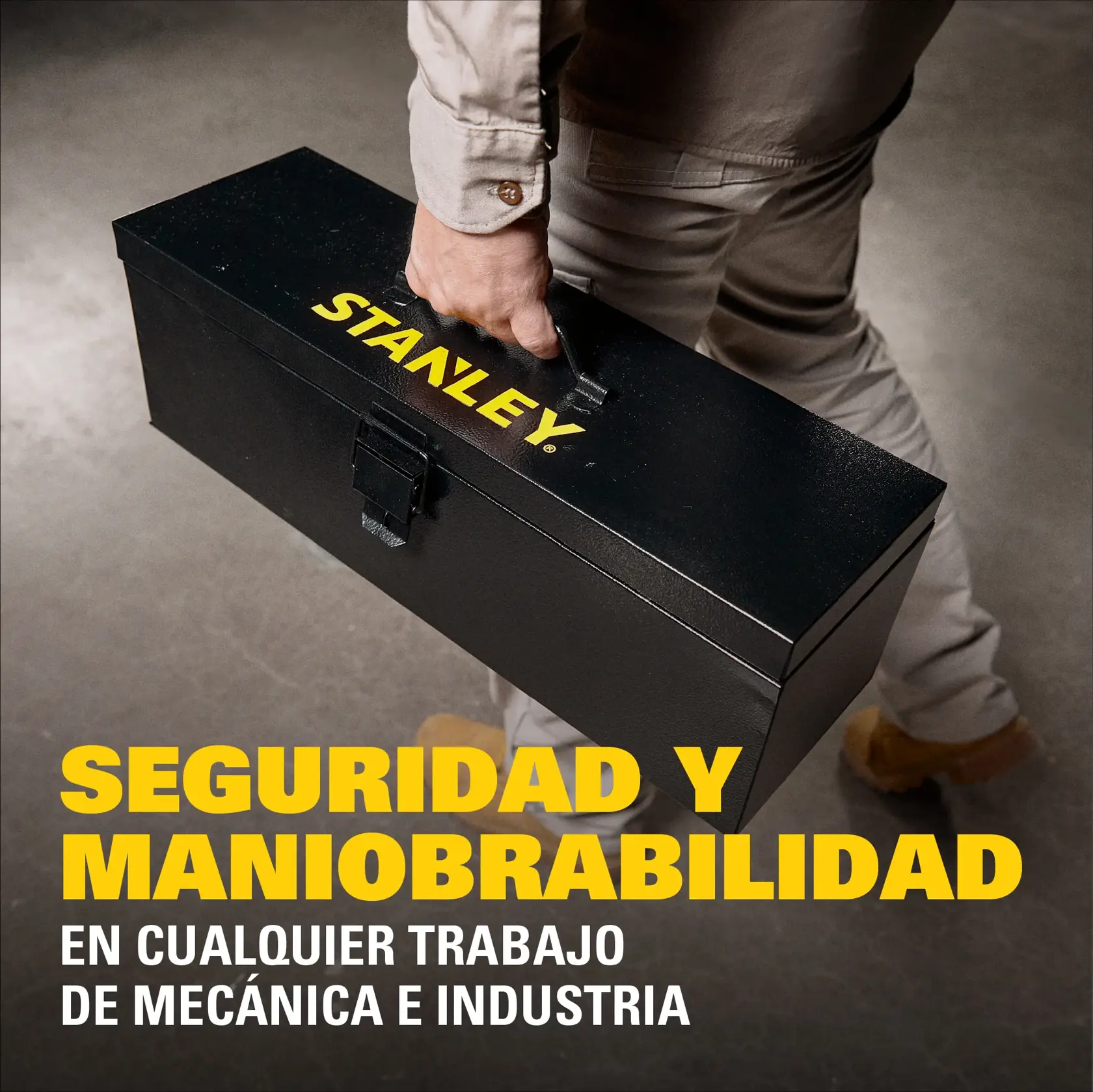 Una persona vestida con ropa beige y zapatos marrones sostiene una caja de herramientas negra de Stanley. La caja tiene el logo de Stanley en amarillo. El texto enfatiza la seguridad y maniobrabilidad para cualquier trabajo de mecánica e industria.
