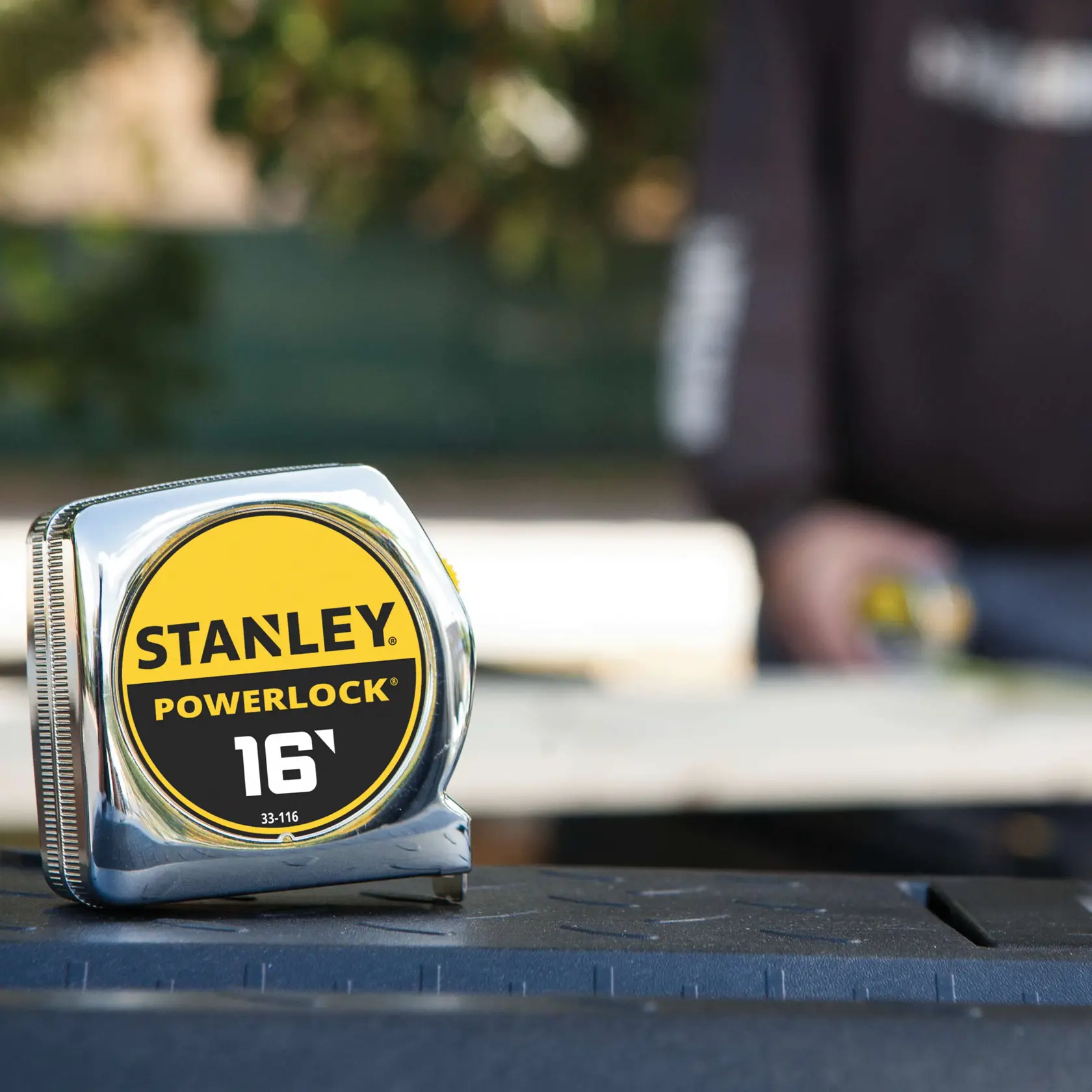 Cinta métrica STANLEY 33-116 con carcasa cromada y etiqueta amarillo-negro, fotografía en exterior.
