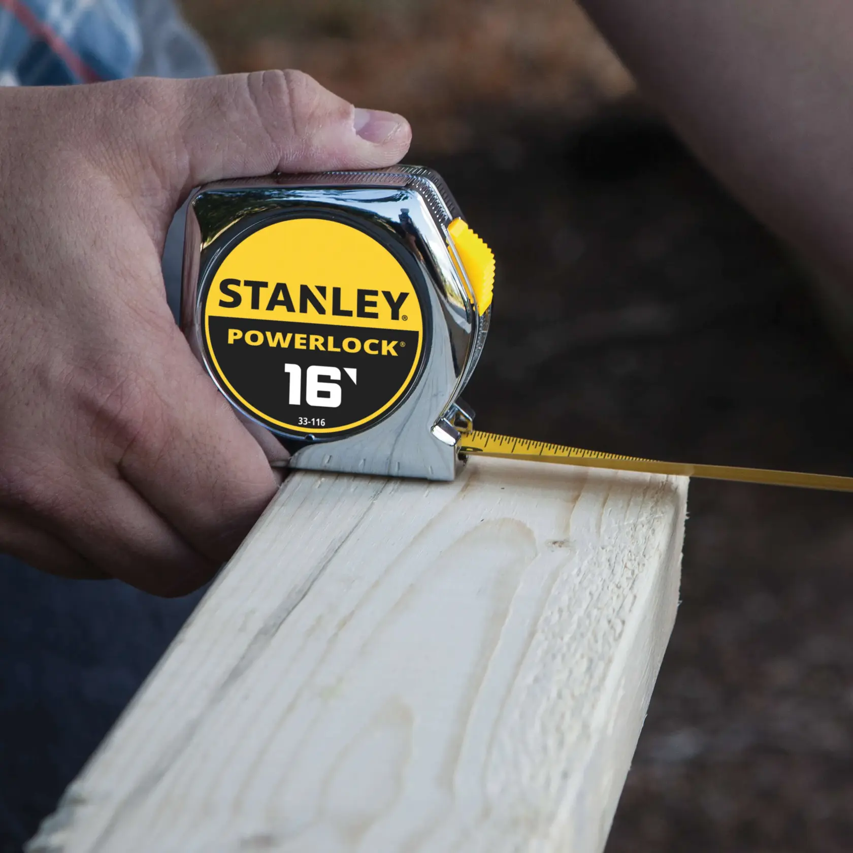STANLEY 33-116 PowerLock cinta métrica midiendo una tabla de madera, vista en primer plano.