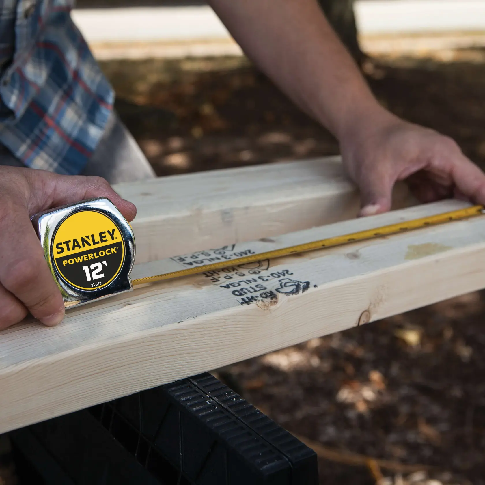 Stanley 33-312 cinta métrica utilizada para medir una tabla de madera al aire libre, fotografía en primer plano.