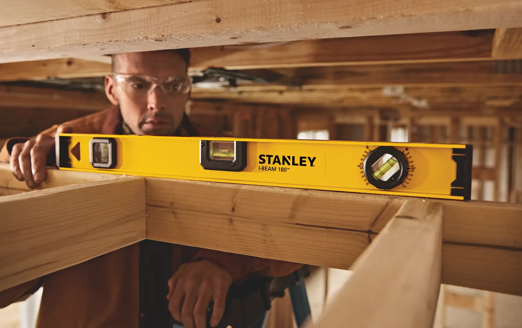 Fotografía del nivel STANLEY 42-324 I-Beam 180° usado sobre vigas de madera en obra en construcción.
