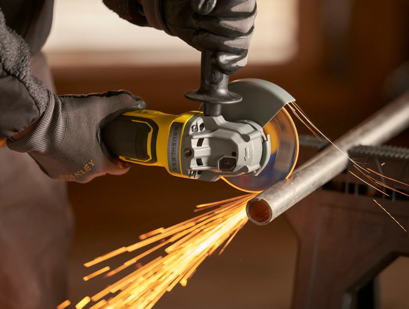 Stanley SBG700M2K amoladora angular cortando tubo metálico, con chispas, fotografía en primer plano.