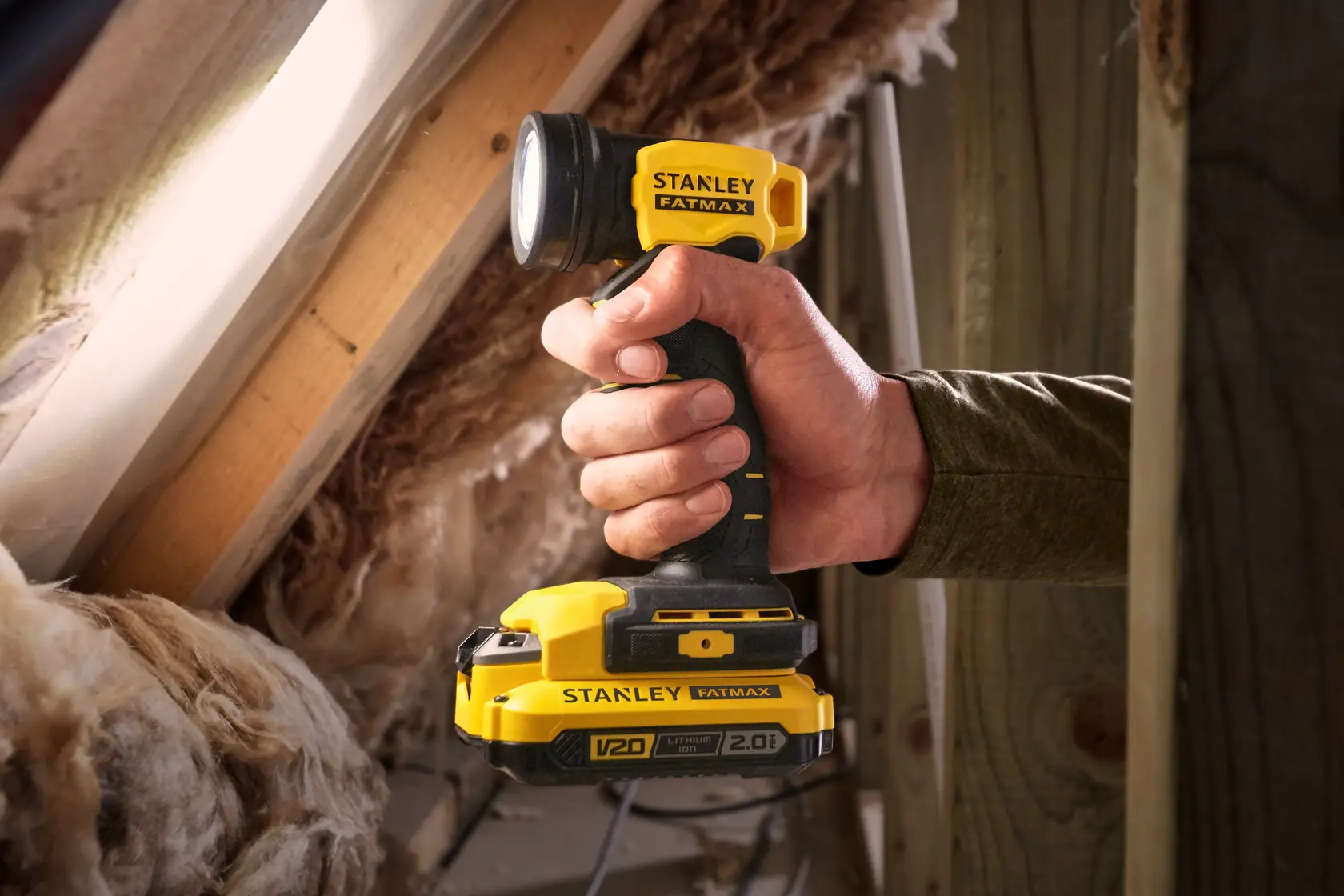 Stanley SCL020 linterna inalámbrica de mano utilizada en un ático, con diseño amarillo y negro.