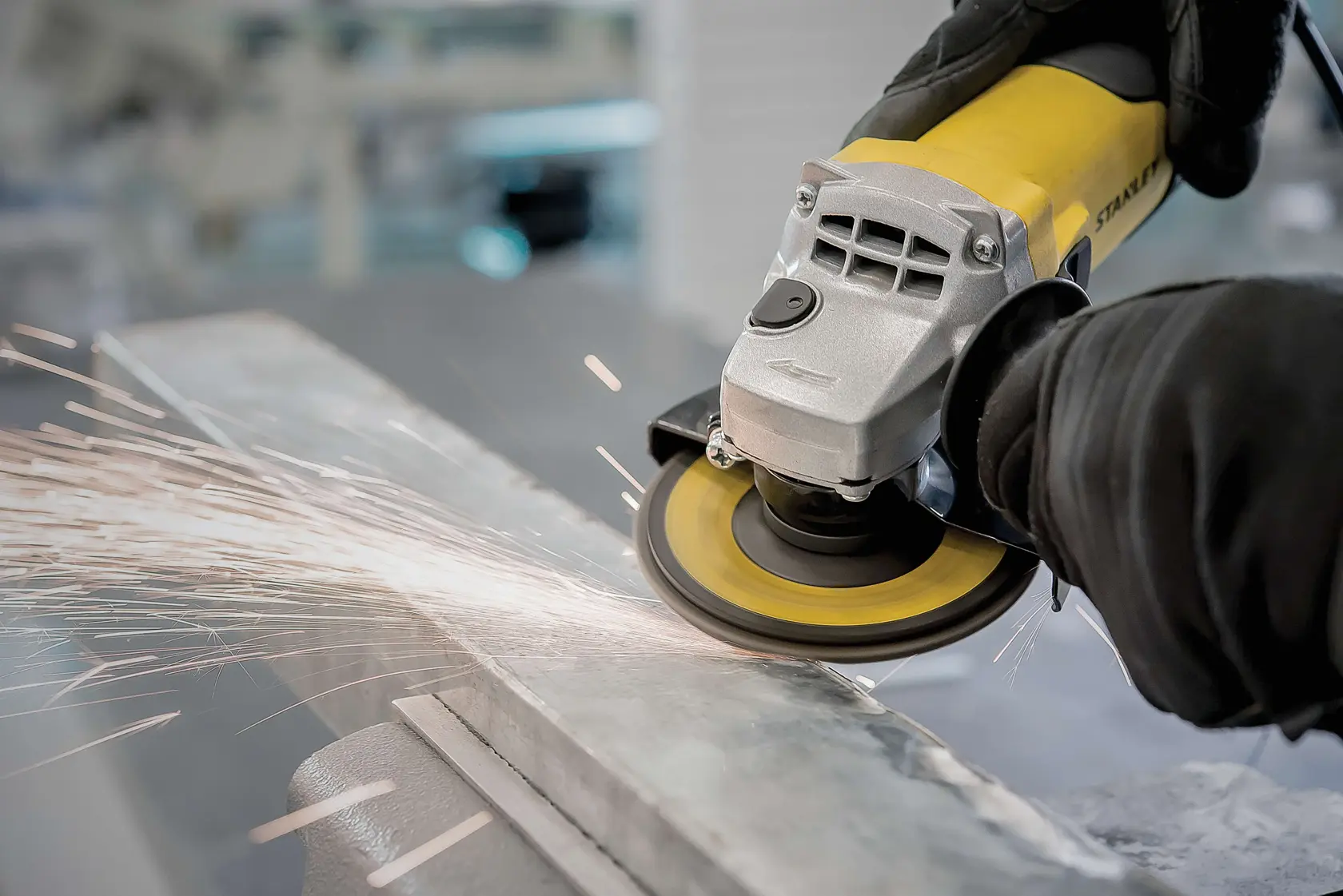 STANLEY STA4120FZ esmeriladora angular en uso pulido de metal, primer plano con chispas, fotografía de producto.